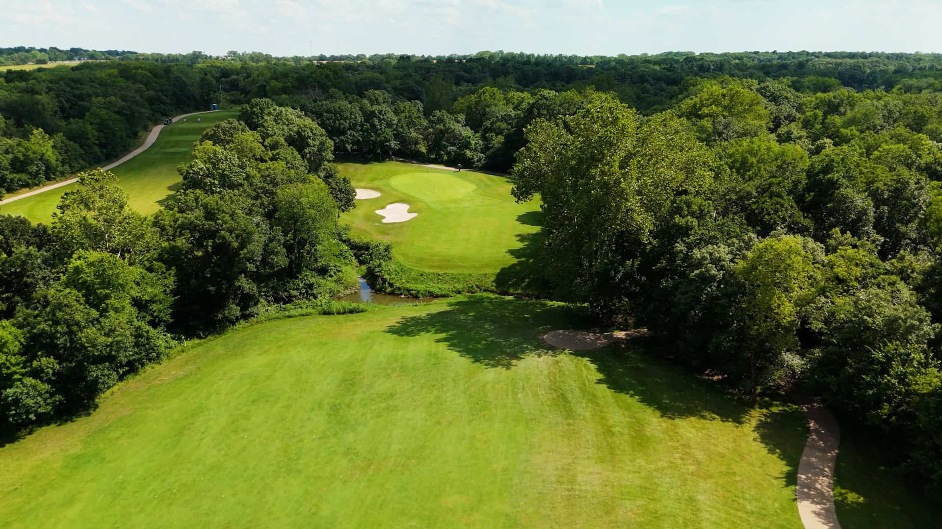 Cinematic drone shot of a pristine golf course fairway at golden hour